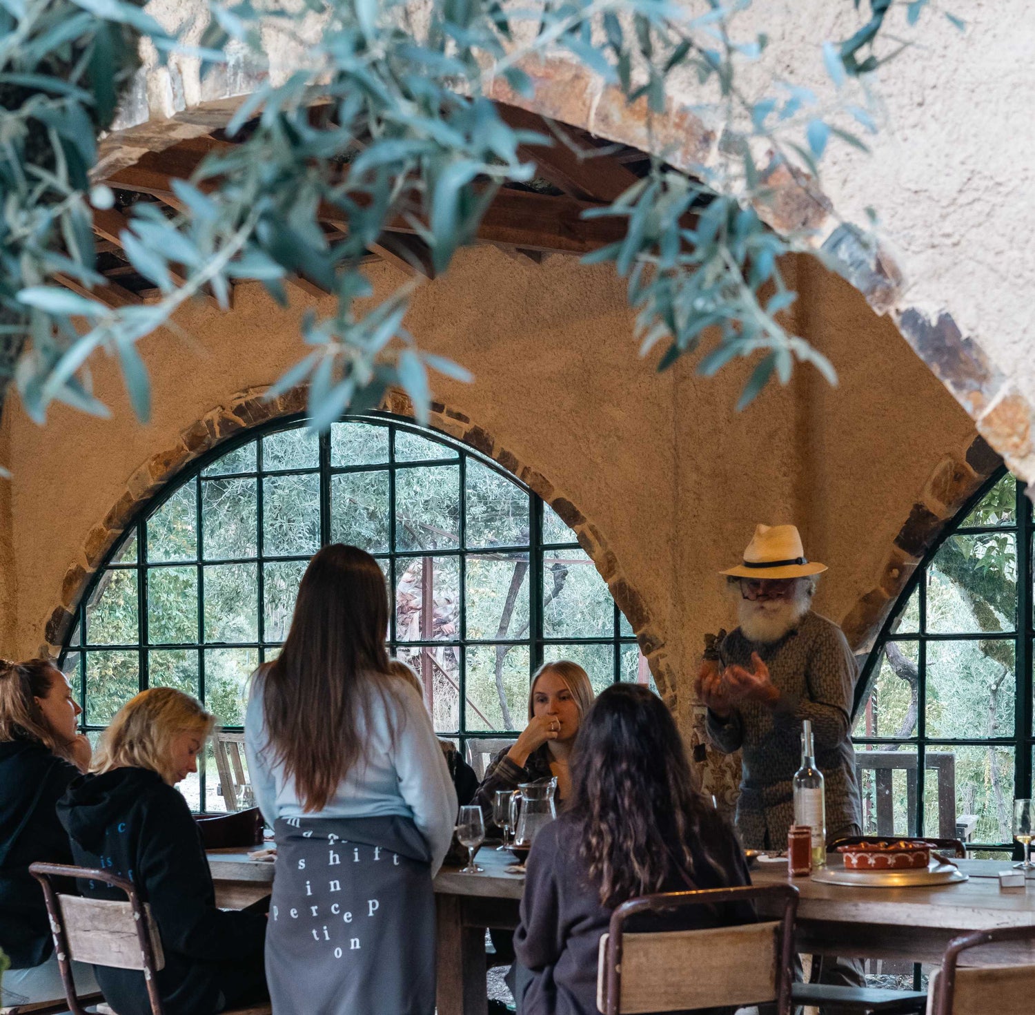 People dining outdoors at a winery restaurant with large windows and rustic decor.